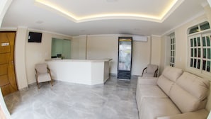 Un moderno vestíbulo de hotel con recepción, zona de estar y un ventanal grande.