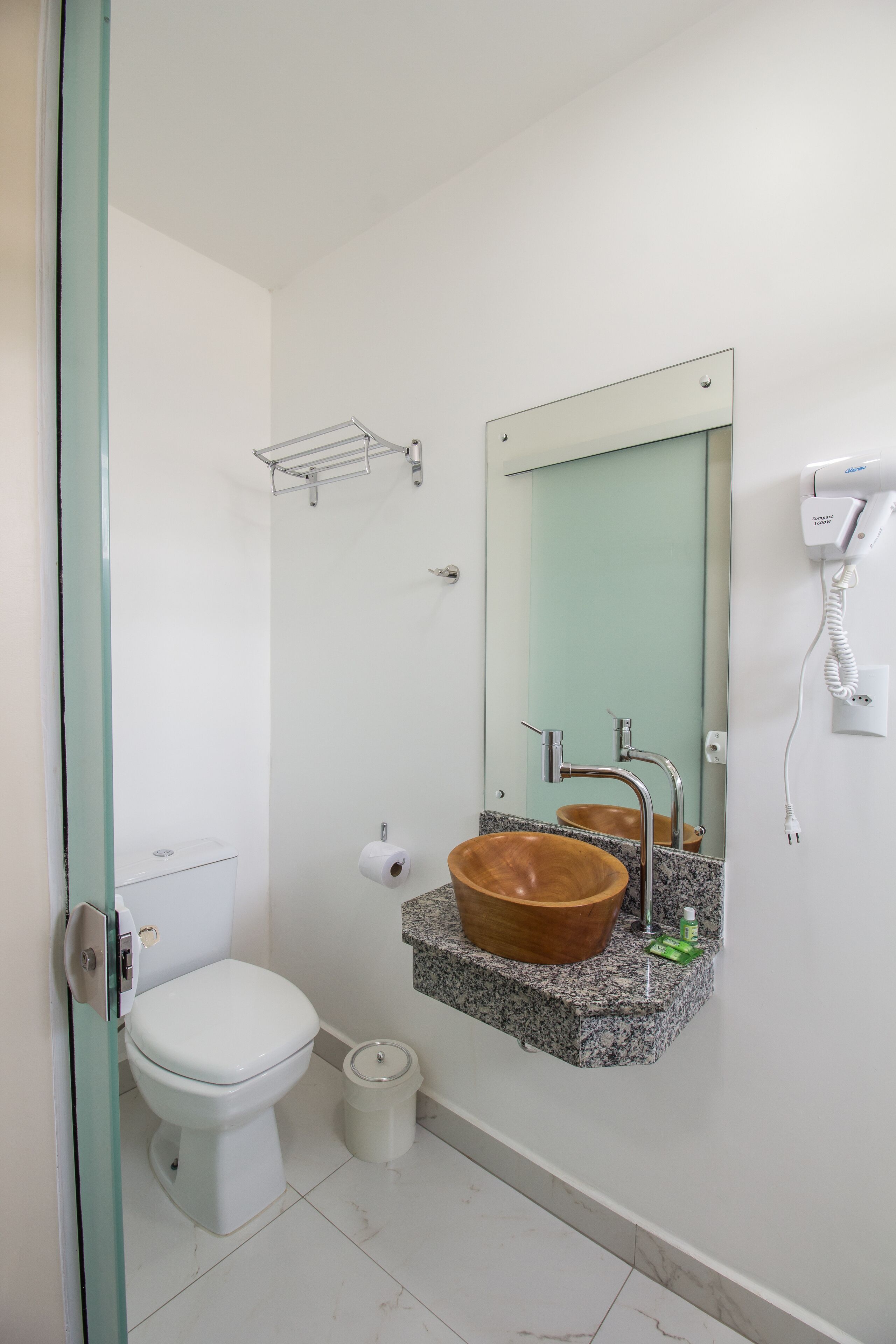 A bathroom with a white toilet, a wooden sink, a mirror, and a hairdryer on the wall.