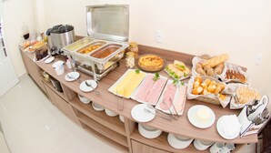 Un bufé con diversas opciones de comida, incluyendo carnes, quesos y pastelería.
