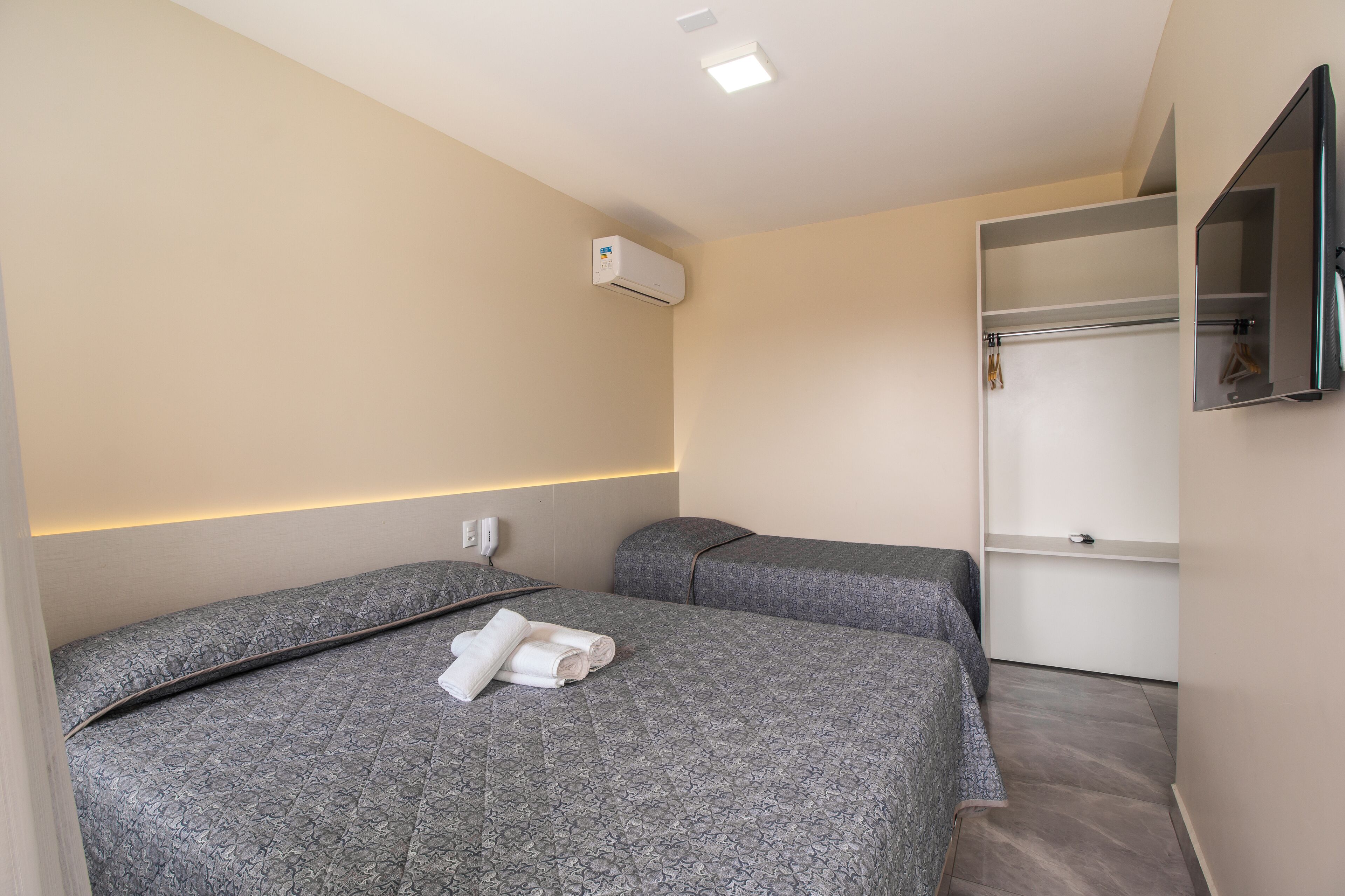 A hotel room with two beds, a wardrobe, and a mirror.