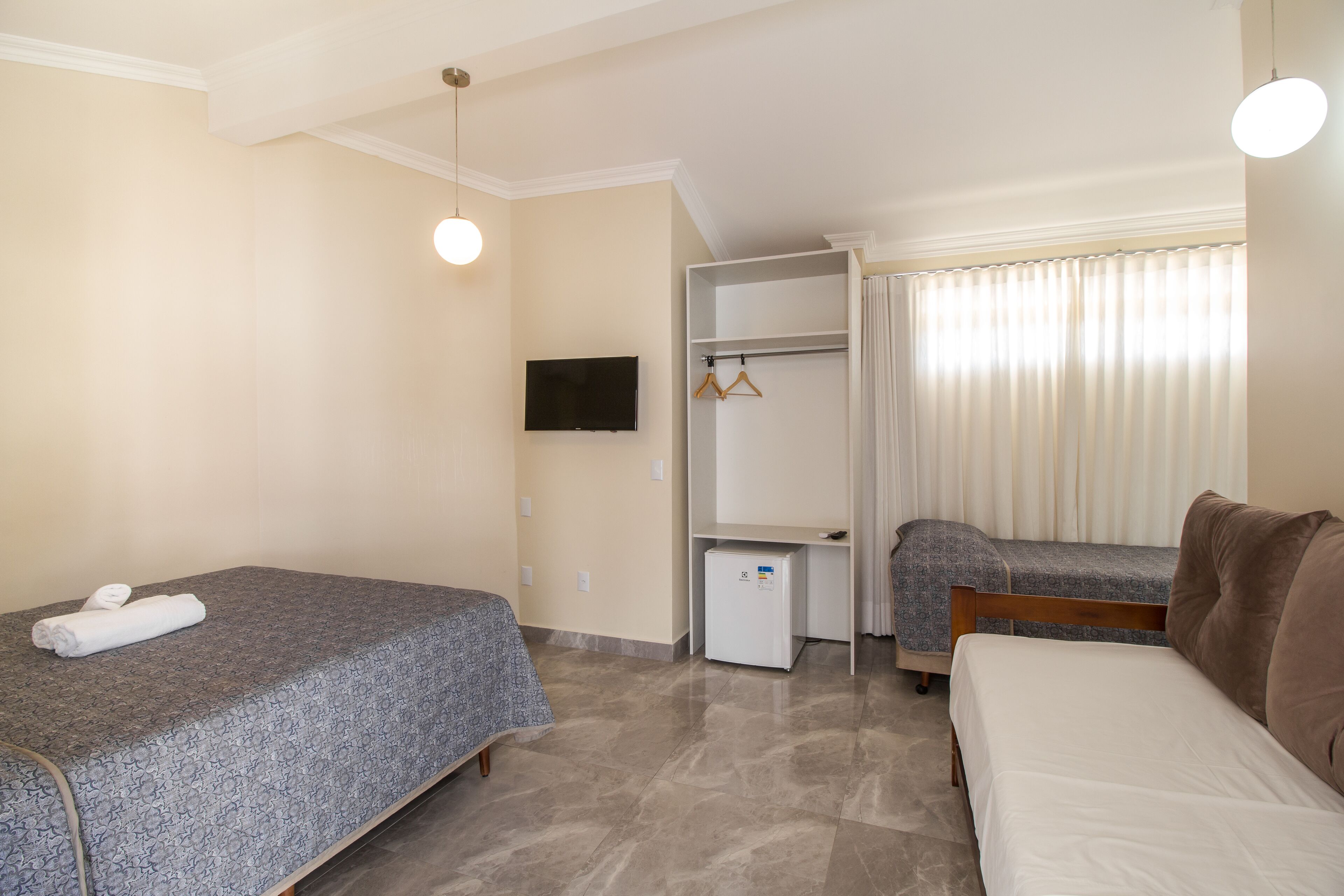Camera da letto con due letti, TV, armadio e un piccolo frigorifero.