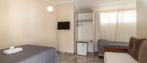 Camera da letto con due letti, TV, armadio e un piccolo frigorifero.