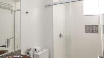 Uma casa de banho moderna com chuveiro de vidro, toucador de madeira e sanita branca.