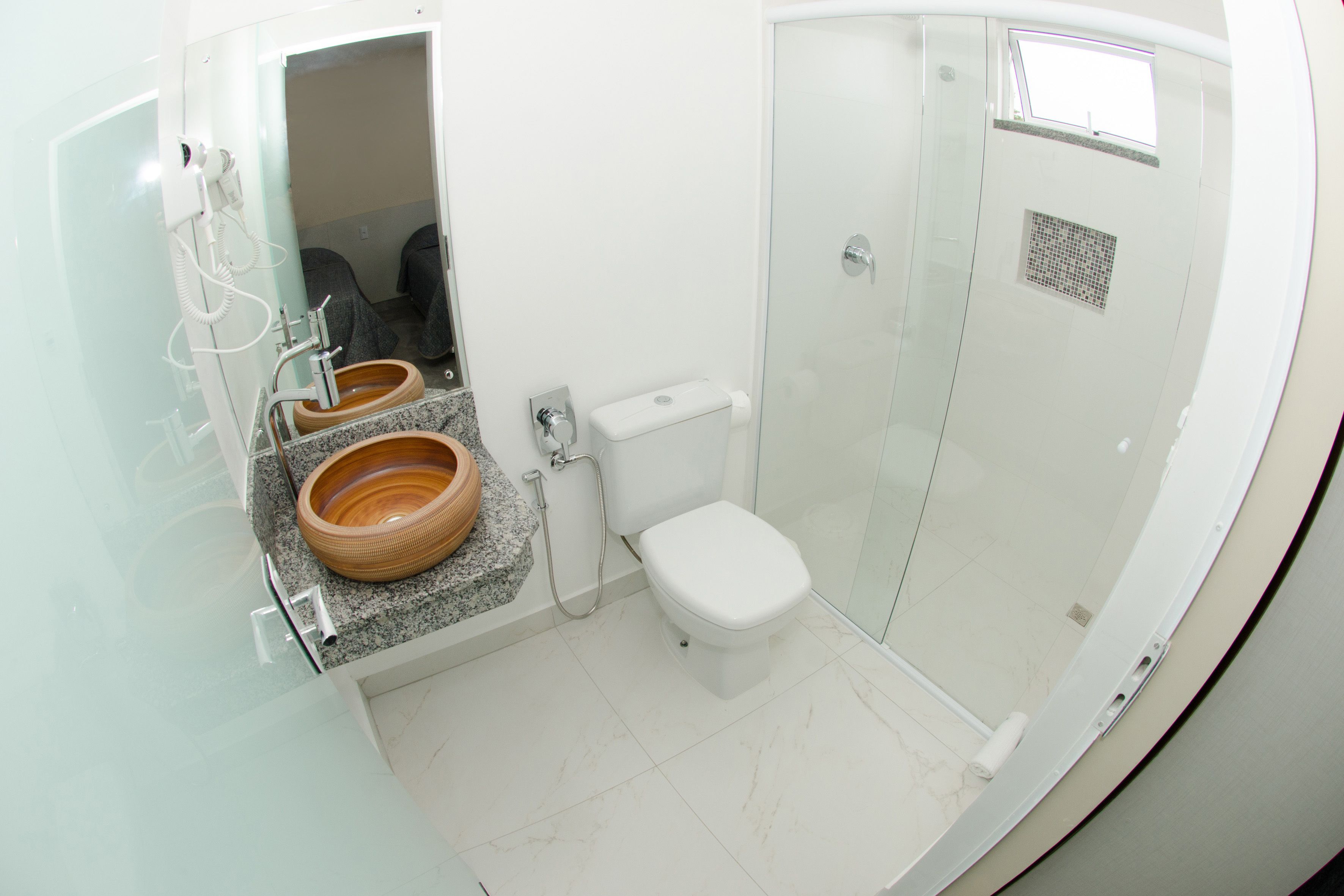 A modern bathroom with a glass-enclosed shower, a toilet, and a vanity with a wooden bowl sink.