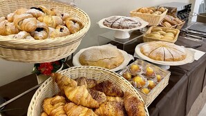 A buffet table with various baked goods including croissants, bread, and pastries. - Hotel Quisisana Riccione (Riccione)