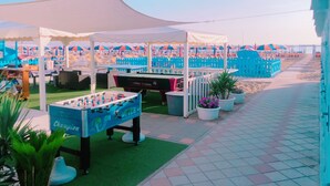 A beachside area with a foosball table, outdoor seating, and umbrellas. - Hotel Quisisana Riccione (Riccione)