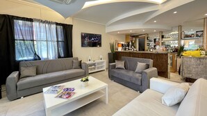 A modern living room with a sofa, a coffee table, and a TV. - Hotel Quisisana Riccione (Riccione)