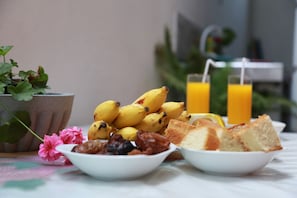 A breakfast setting with bananas, bread, and a flower on a table. - New planet guest (Mirissa)