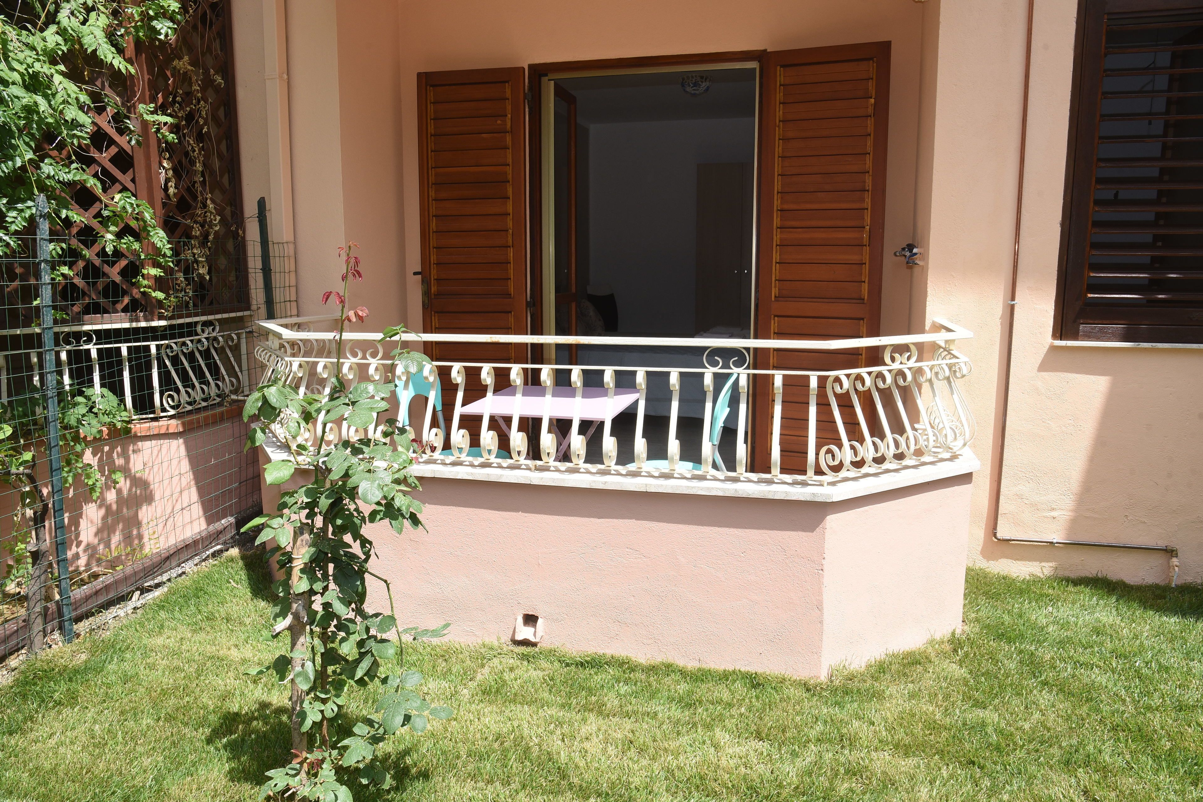 A small outdoor balcony with a metal railing, a table, and a chair.
