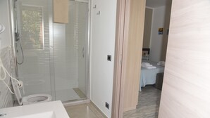 Een badkamer met een douchecabine van glas, een wit toilet en een wastafel.