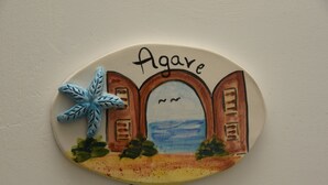 Een decoratief object met de tekst 'Agave' en een gestileerd gebouw met bogen en een palmboom.