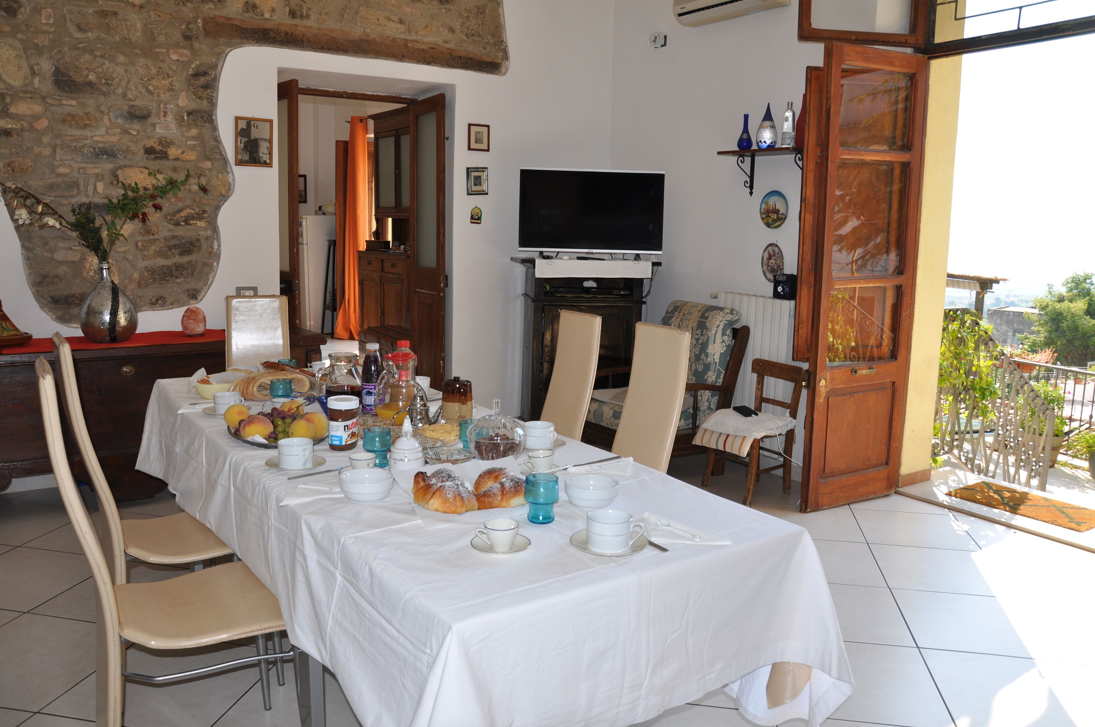 A dining area with a table set for breakfast, a television, and a view of the outdoors.