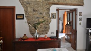 A room with a stone wall, a wooden door, a small table with a vase, and a television. - B & B La Panoramica (Villapiana)