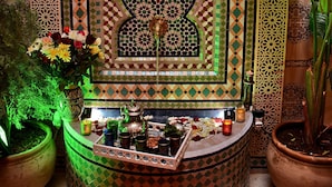 A room with intricate tile work, a decorative alcove with a mirror, and a potted plant. - Riad Dar Leuleu (Marrakech)
