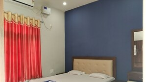 Una cama bien hecha con cabecera de madera, cortina roja y unidad de aire acondicionado blanca en la pared.