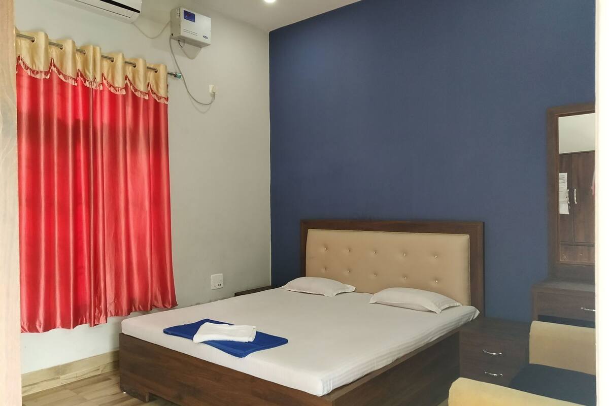 Un dormitorio con cama, cabecera de madera, cortina roja y aire acondicionado de pared.