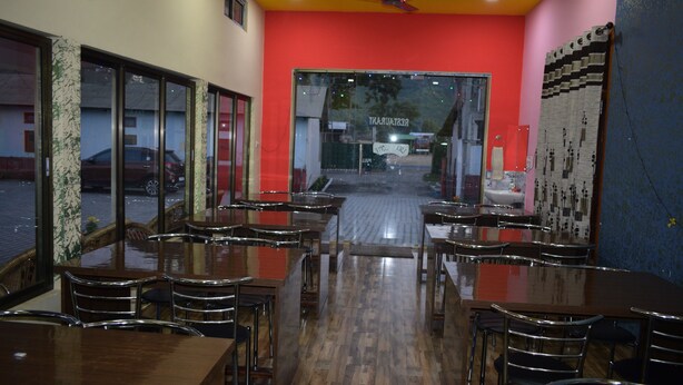 Un restaurante con una decoración en tonos rojo y amarillo, suelo de madera y vistas a la calle a través de amplios ventanales.