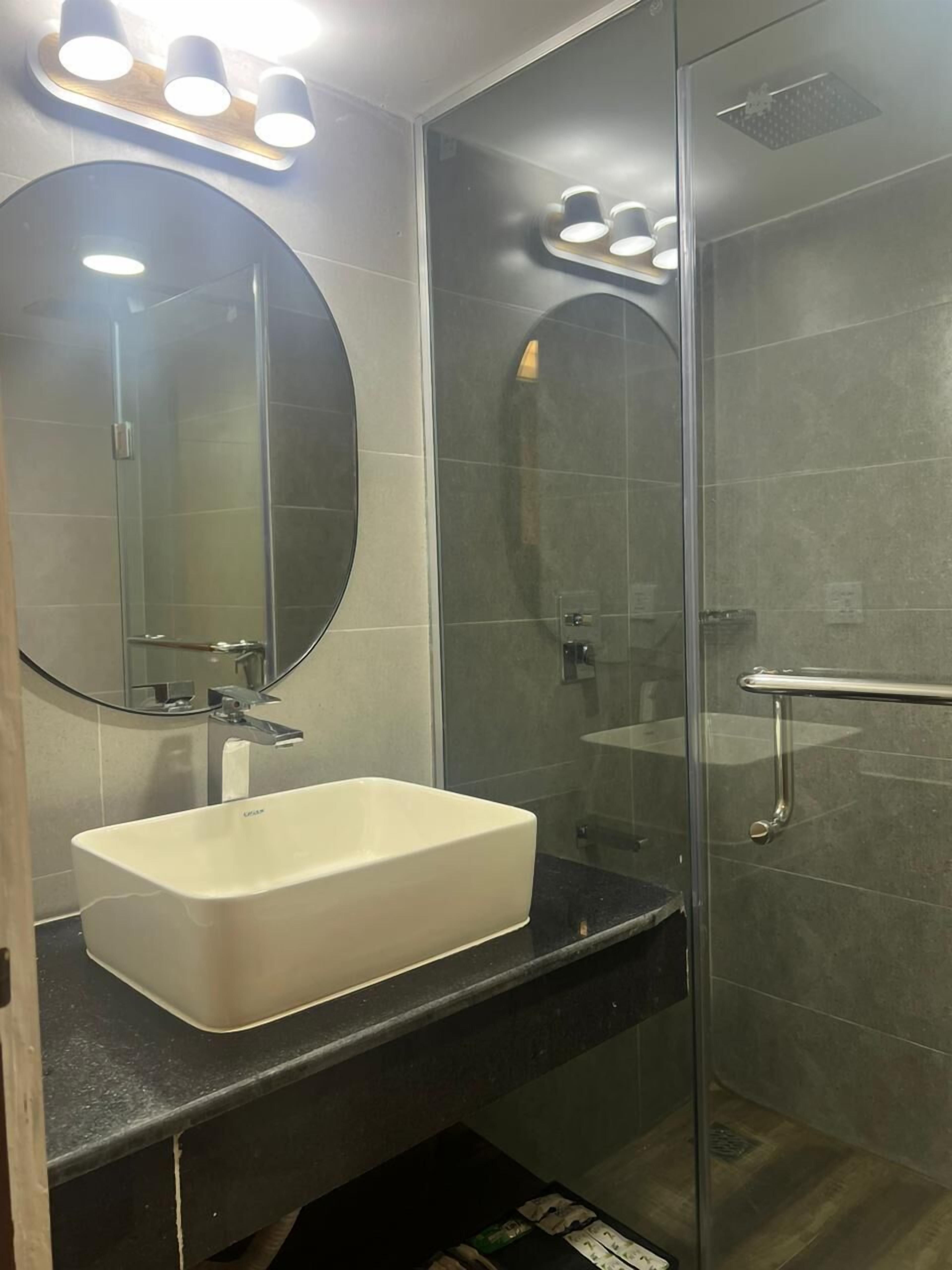 A modern bathroom with a white sink, a large mirror, and a glass shower enclosure.