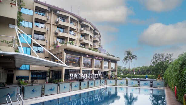 Un hotel con piscina, varios balcones y cielo despejado.