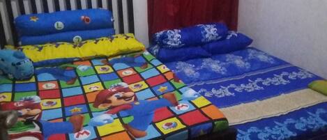Una cama con un edredón y almohadas de diseño colorido con temática de Mario, un cabecero y una cortina roja.