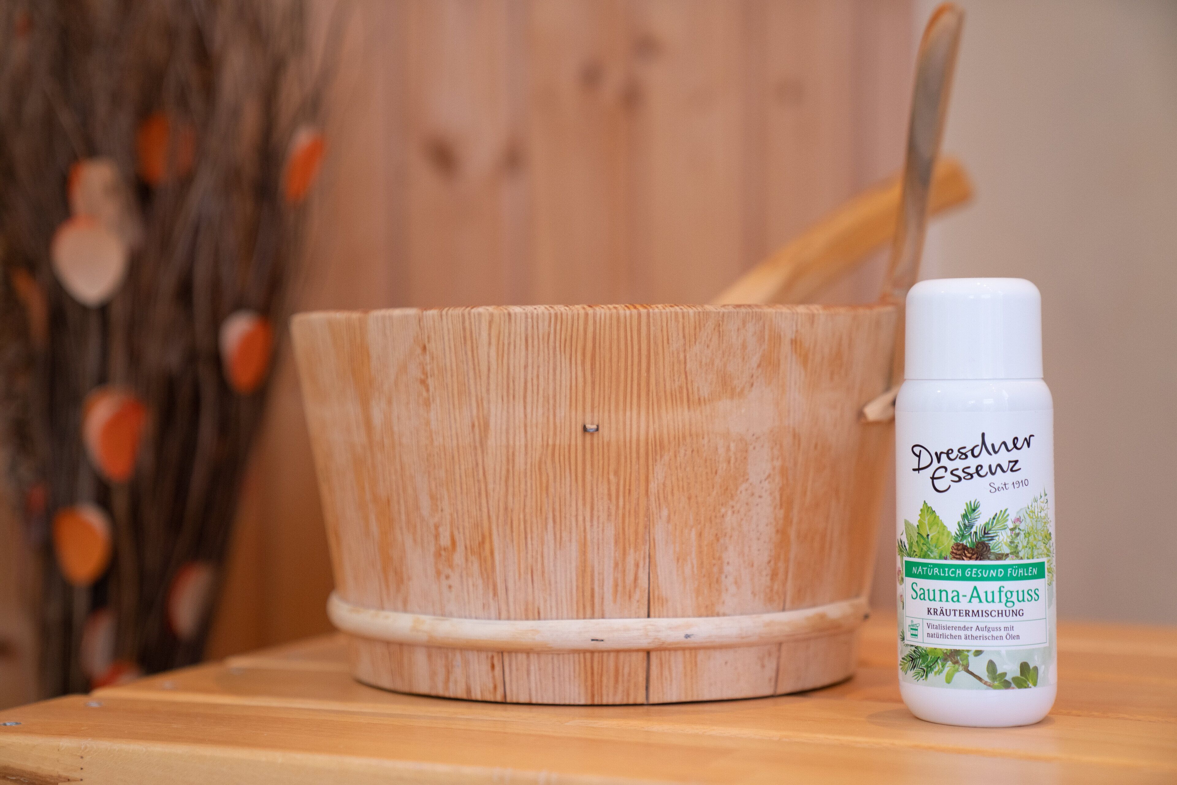Una mesa de masaje de madera con una botella de Dresden Essenz Sauna-Aufguss a su lado.