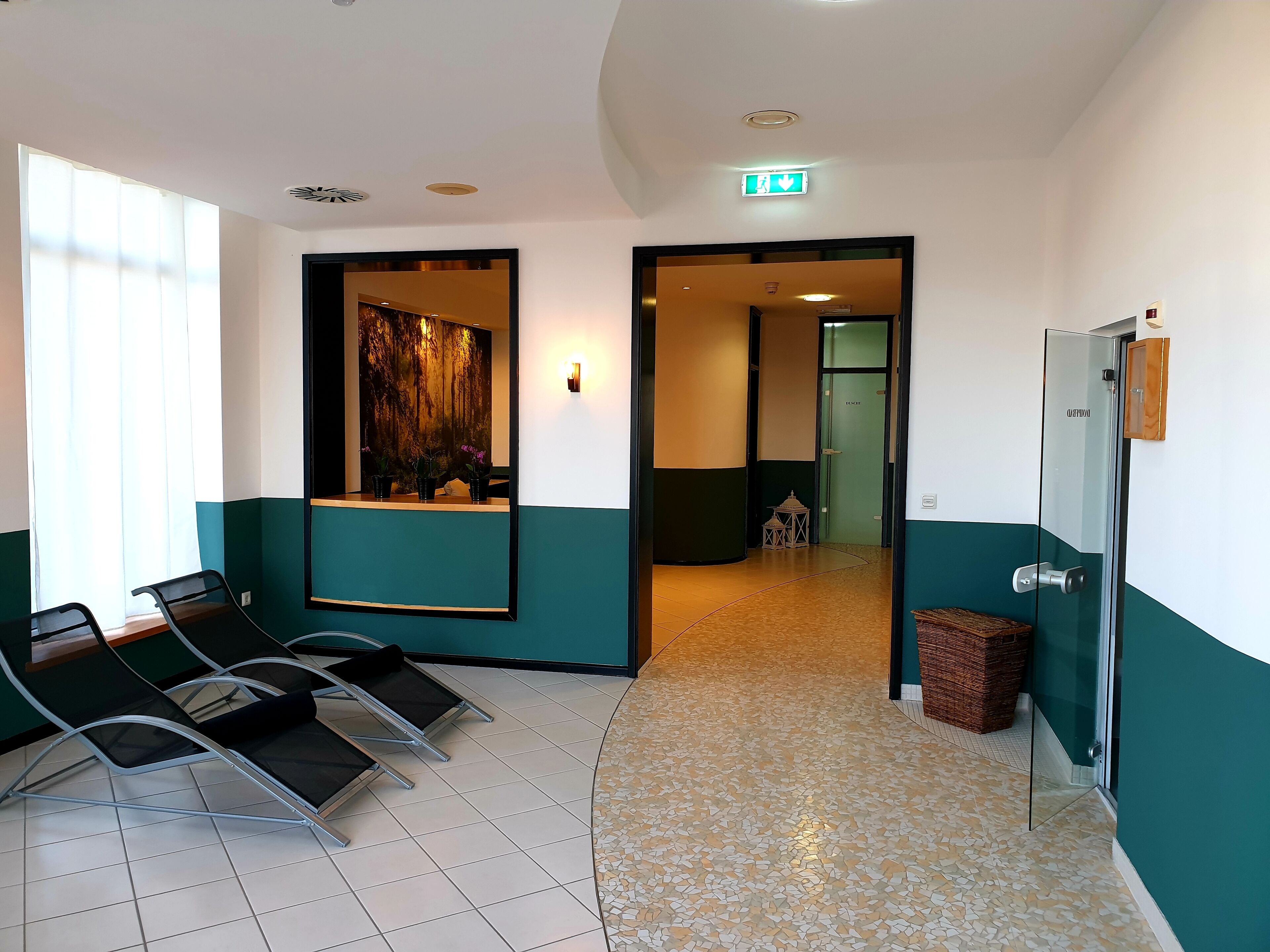 A reception area with a reception desk, chairs, a wall-mounted mirror, and a door leading to a hallway.