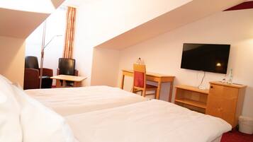A hotel room with two beds, a desk, a chair, a television, and a small cabinet.