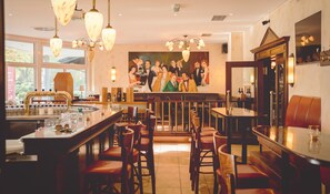 Enjoy meals in a warm and inviting dining area with a bar, comfortable seating, and a beautiful painting above.