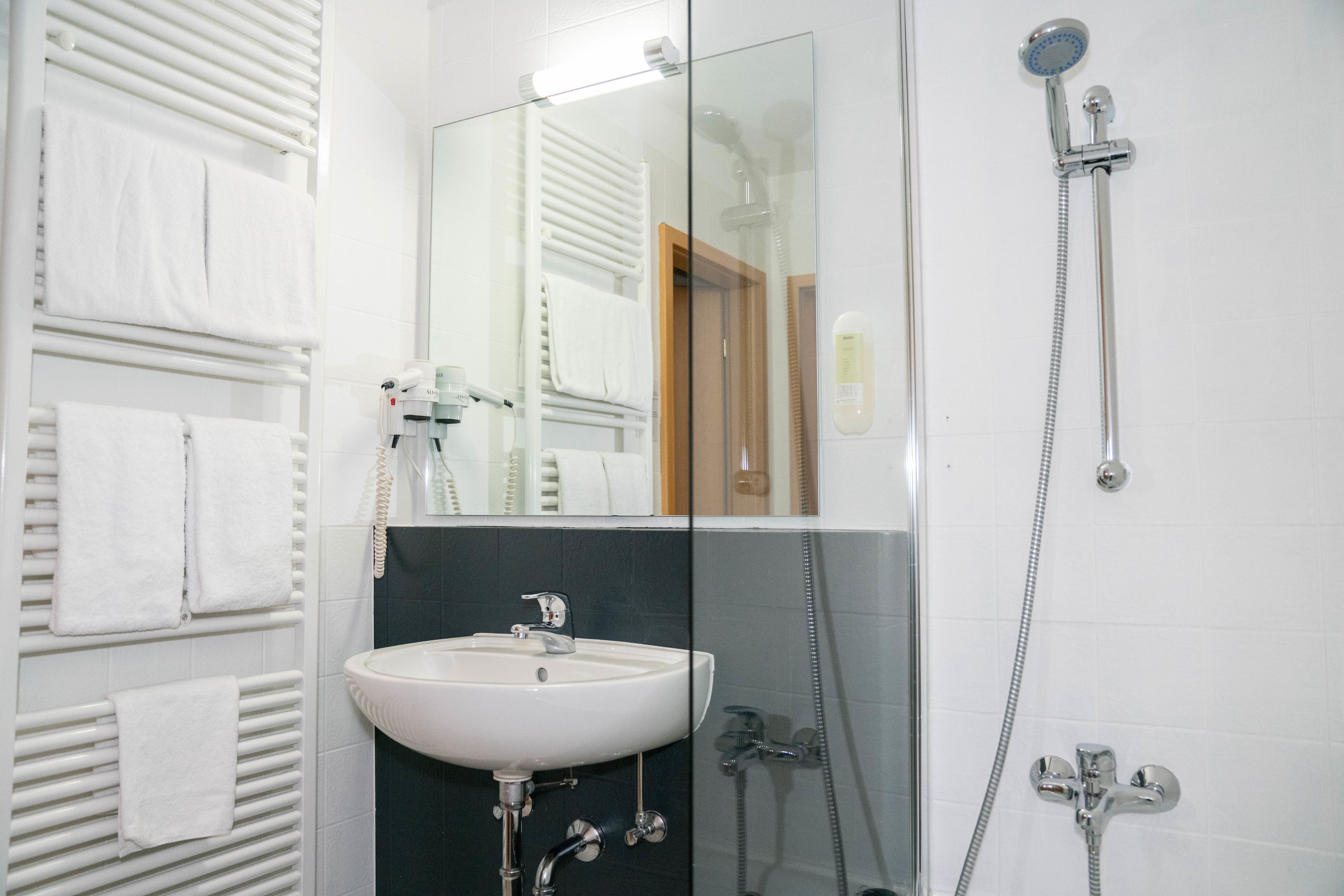 A bathroom with a white sink, a glass shower enclosure, and a mirror.