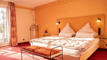 A hotel room with a large bed, a bedside table, a nightstand, a window with curtains, and a view of the outdoors.