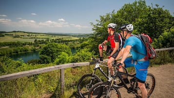 Two cyclists on a dirt path with a scenic view of a lake and hills.