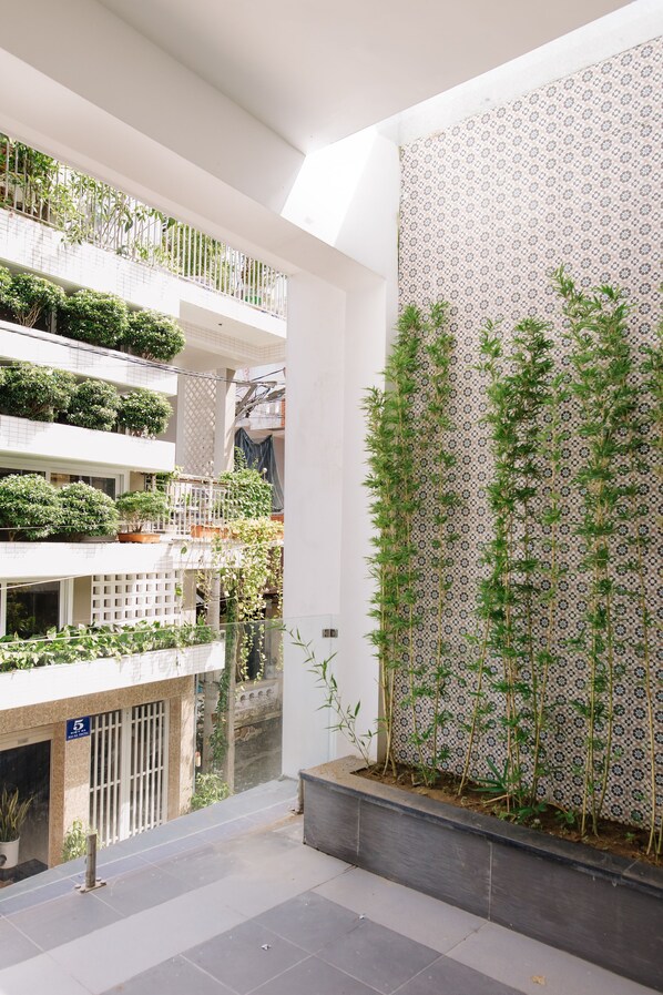 A multi-level atrium with indoor plants, a patterned wall, and a tiled floor.