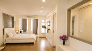 Un dormitorio moderno con una cama grande, una mesita de noche, un espejo y un televisor montado en la pared.
