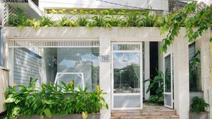 Una casa con fachada de tejas, el número '75C' en la puerta, y un pequeño porche con escalones.