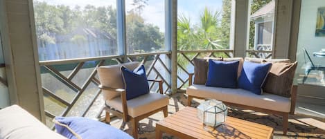 Una habitación soleada con vistas a un lago, amueblada con un sofá, sillas y una mesa de centro.