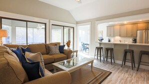 A spacious living area with a sofa, coffee table, and a view of the kitchen. - Short Walk to Beach. Dog-Friendly, Renovated, Bright & Modern Villa with Lagoon Views. (Kiawah Island)