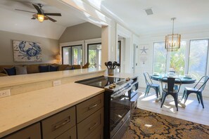A modern kitchen with a large island, built-in oven, and a dining area with a round table and chairs.