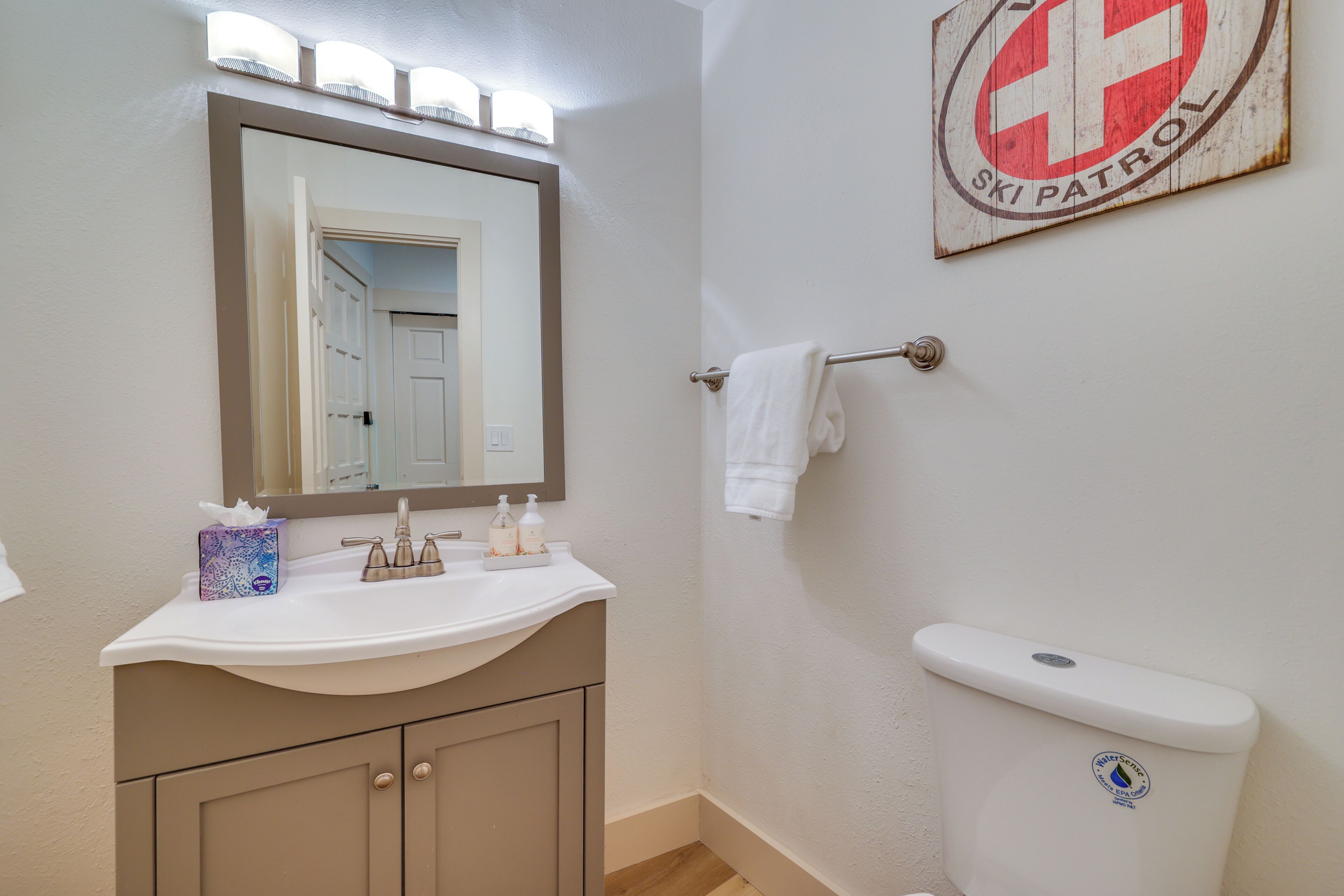 Une salle de bain avec un lavabo, un miroir et des toilettes.