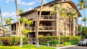Un hotel de varios pisos con balcones, rodeado de palmeras y exuberante vegetación.