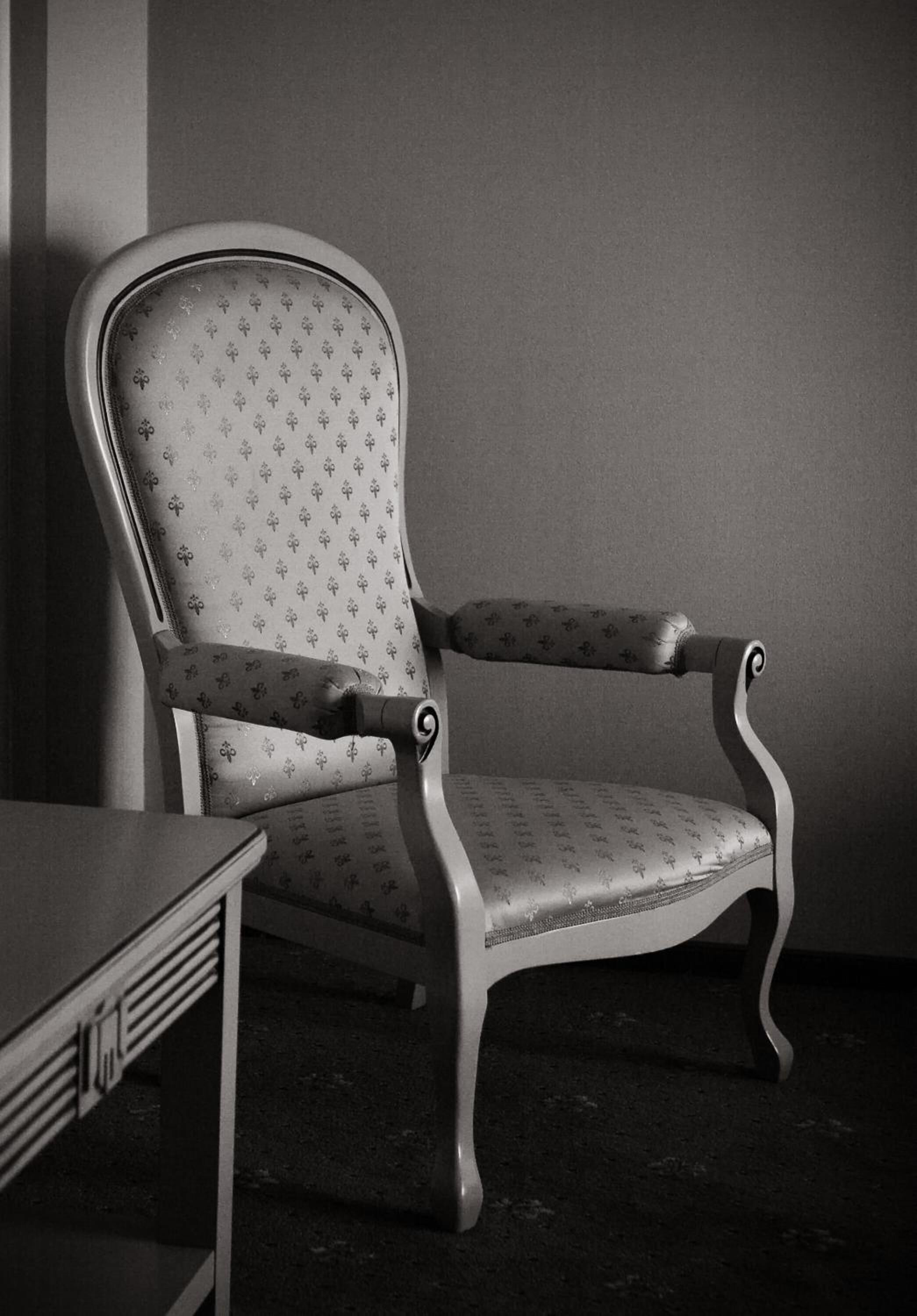 A vintage-style chair with a patterned fabric and curved wooden legs.