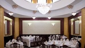A formal dining room with round tables, chairs, chandeliers, and wall sconces. - Hotel Majestic (Iasi)