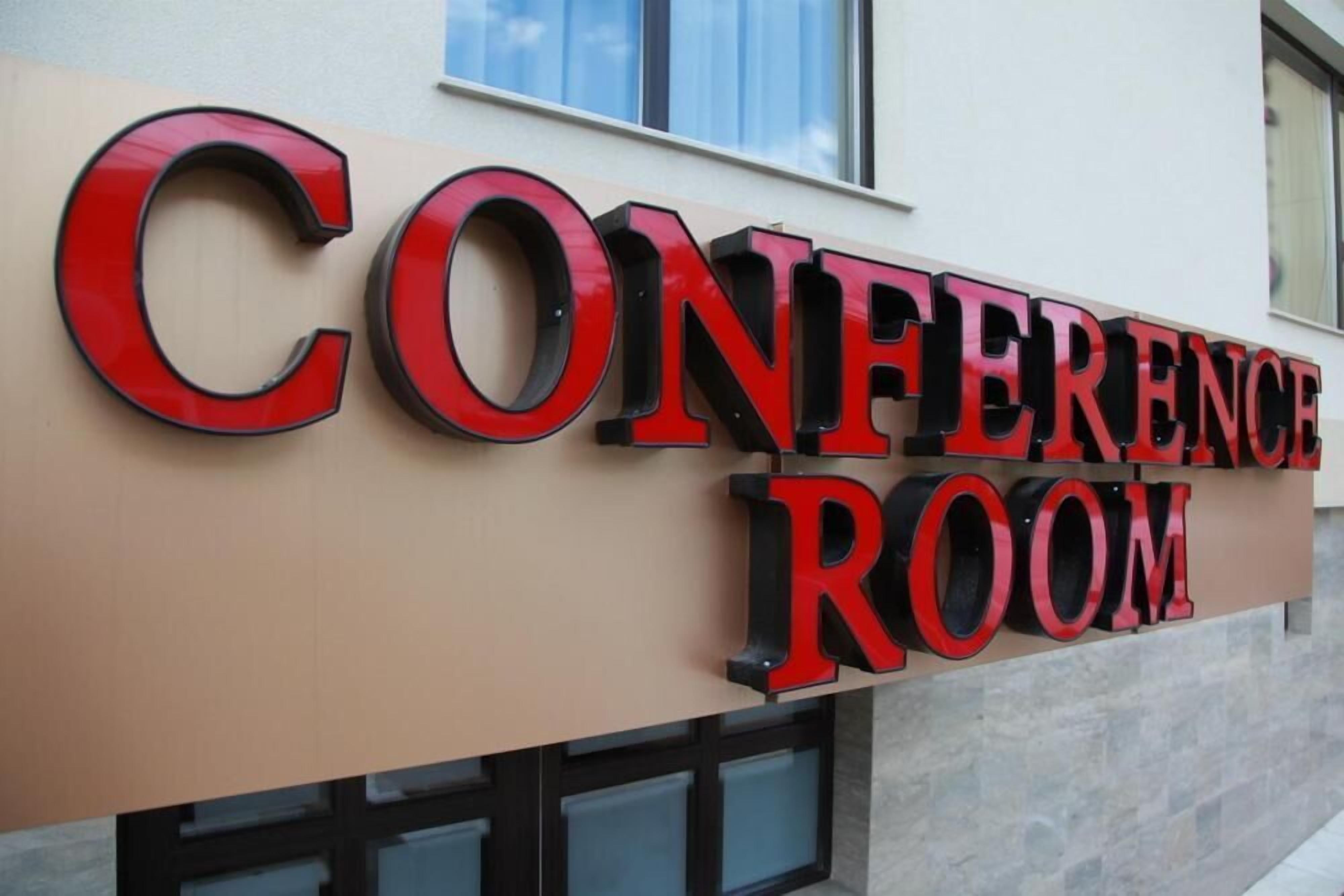 A sign for a conference room with bold, red lettering on a beige background.