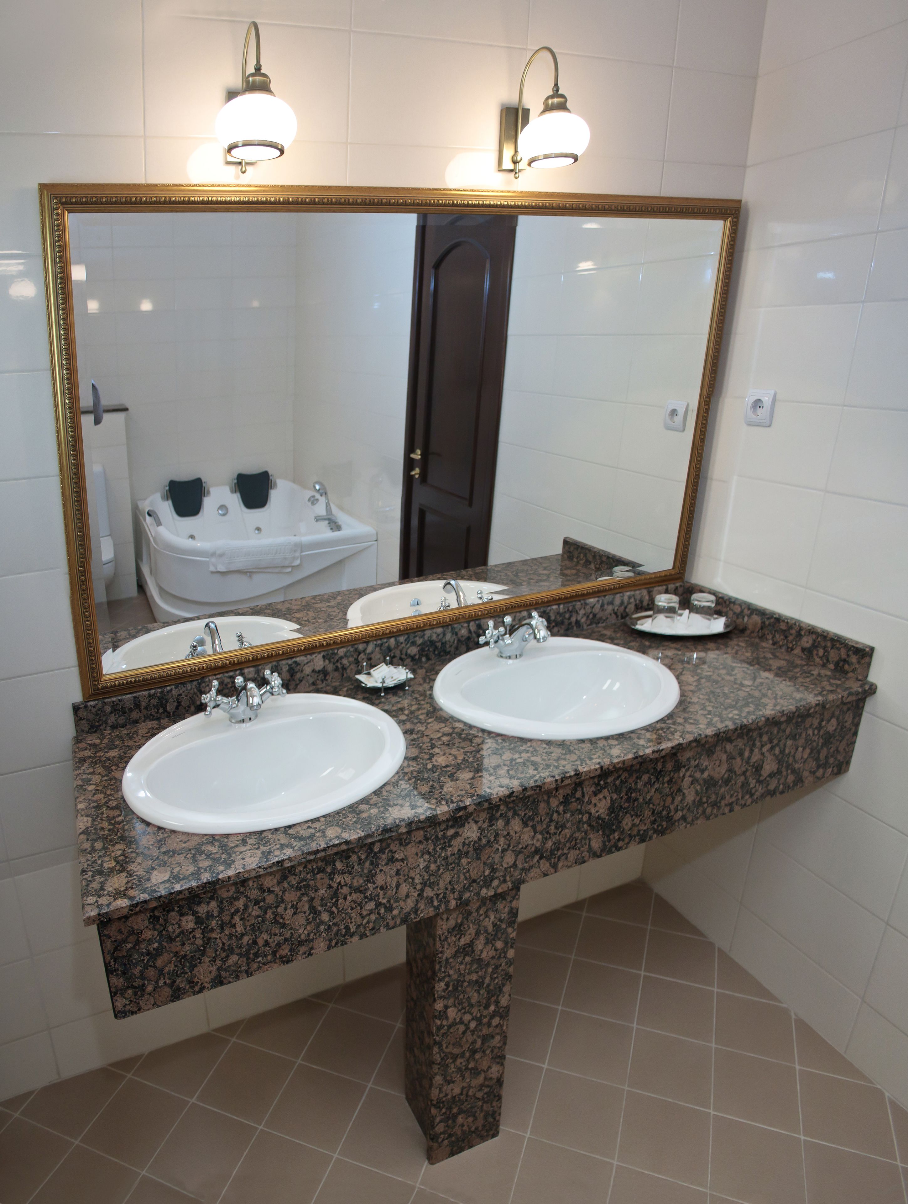A bathroom with two sinks, a large mirror, and a bathtub.