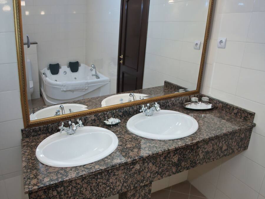 A bathroom with two sinks, a large mirror, and a bathtub.