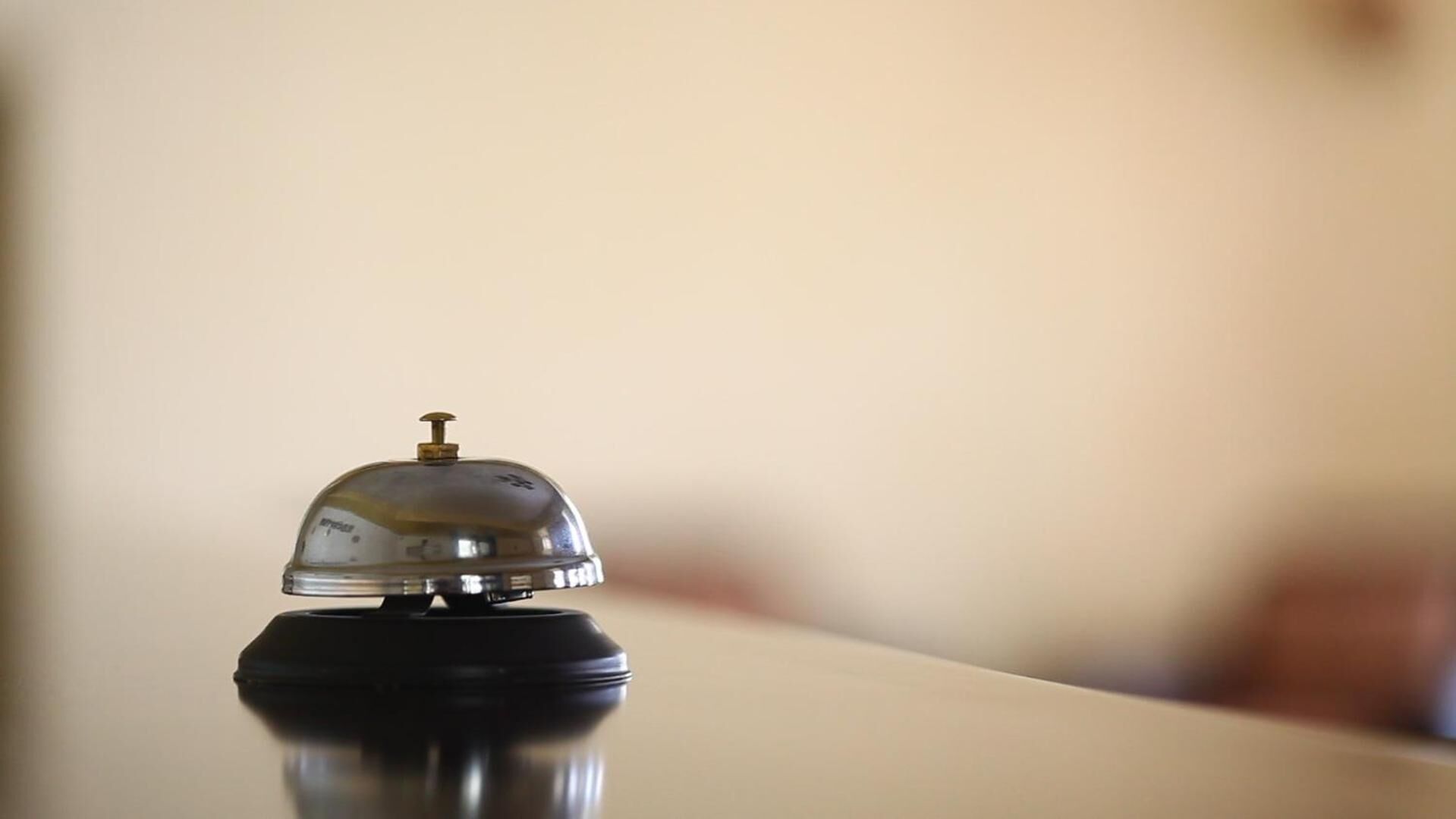 Zona de recepción de un hotel con un timbre sobre un atril.