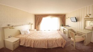 A hotel room with a bed, a desk, a chair, a television, and a window with curtains. - Hotel Majestic (Iasi)