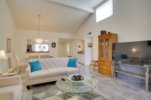 A spacious living room with a large sofa, a glass coffee table, and a television. - 4 Mi to Dtwn Palm Springs: Condo w/ Pool Access (Cathedral City)