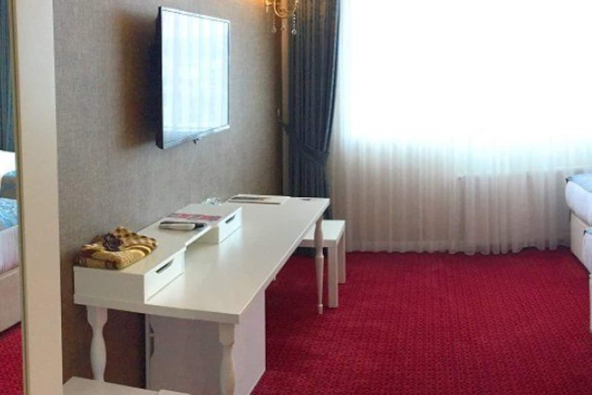 A hotel room with two beds, a desk, and a window with curtains.