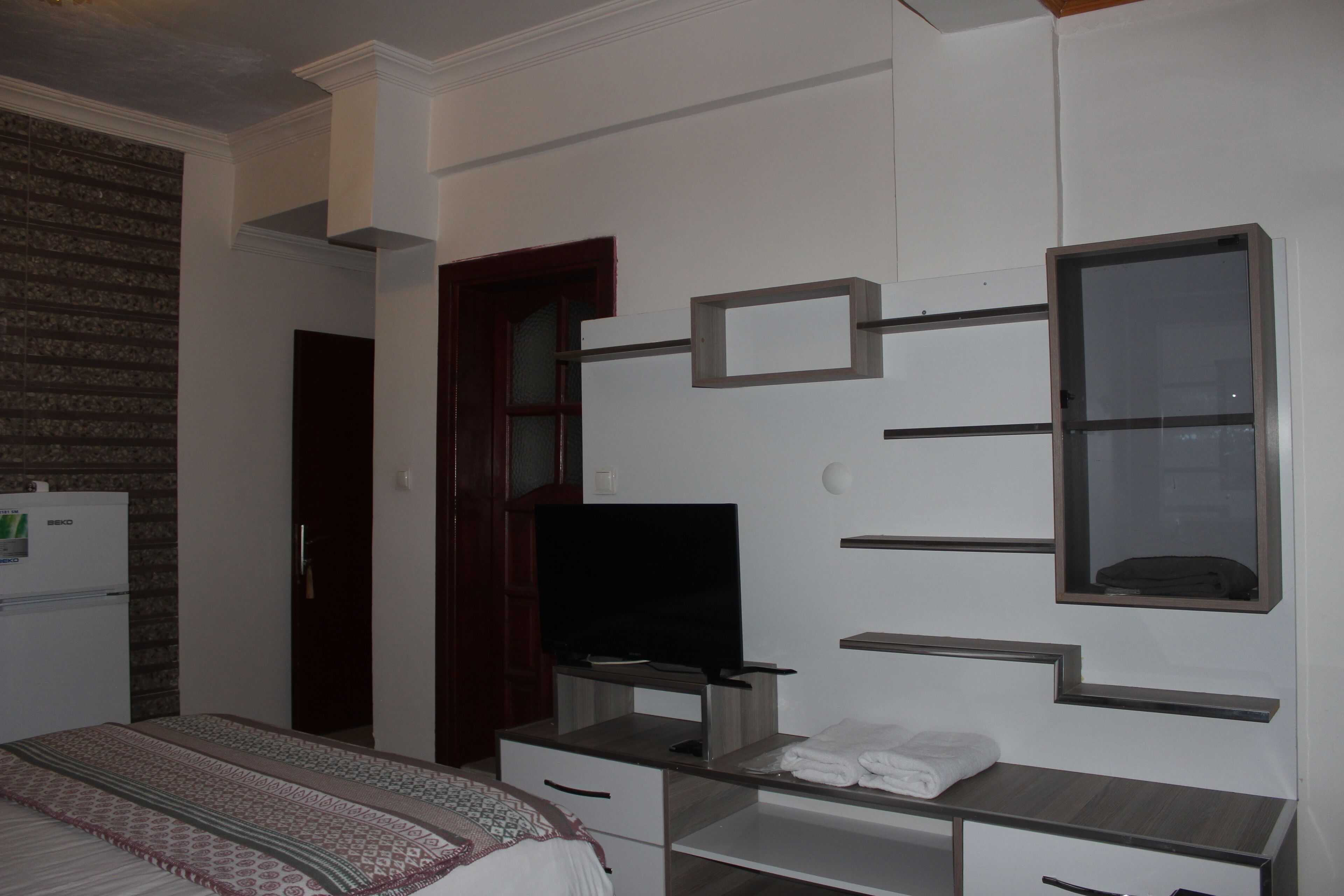 Un dormitorio con cama, televisor, armario y espejo.