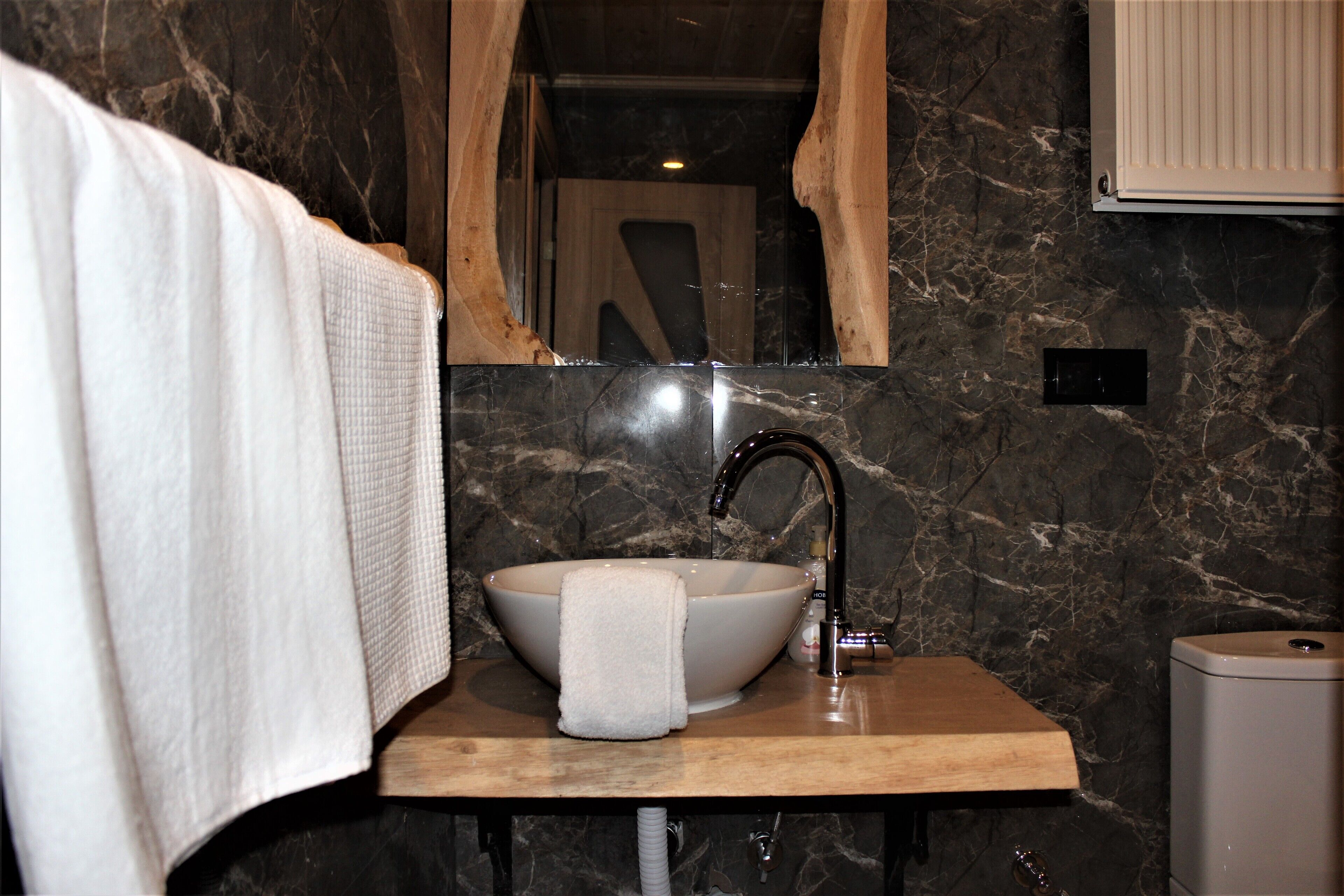 Un bagno con lavabo in marmo, mobile in legno e specchio.